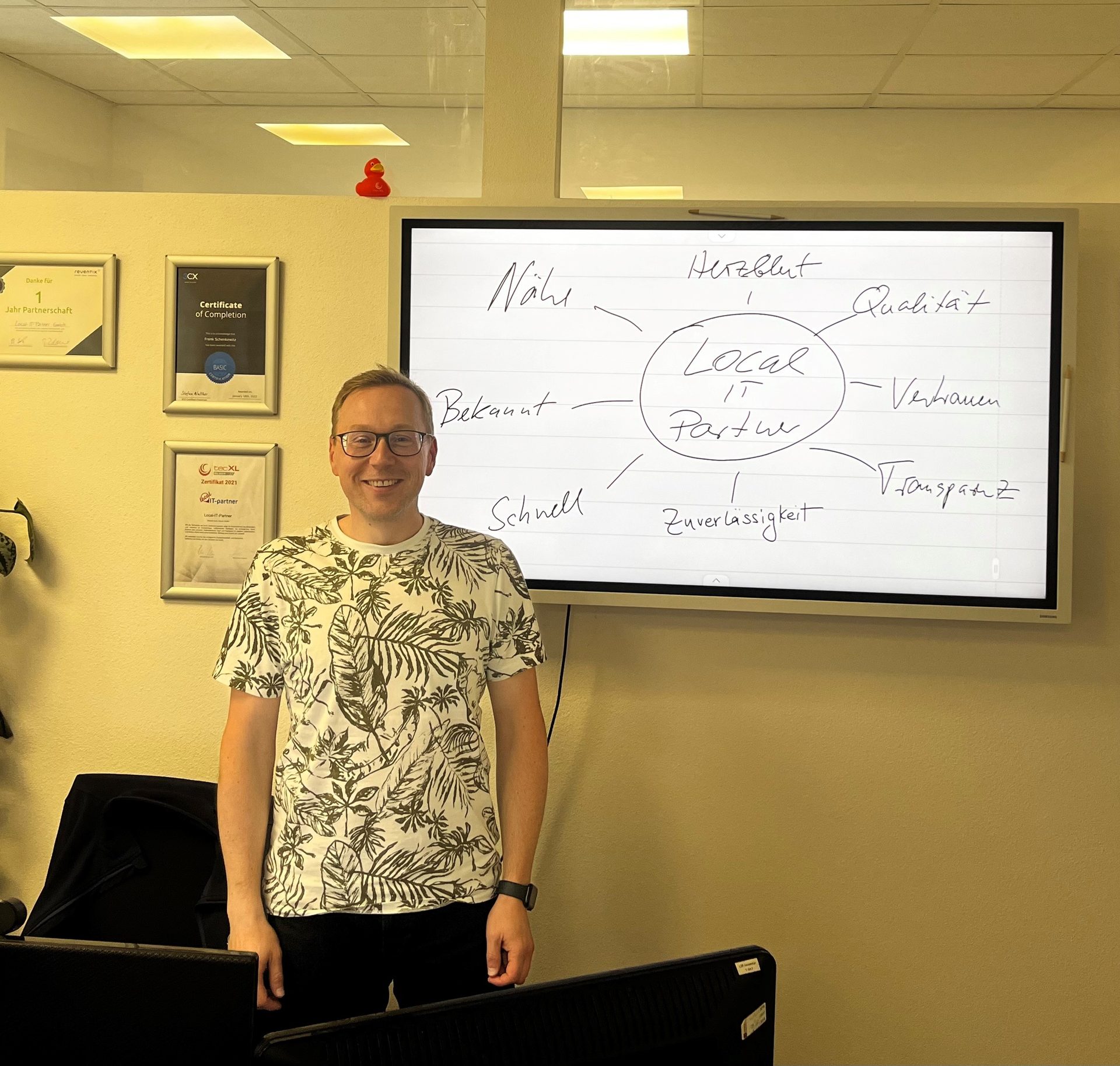 Frank Schenkewitz in the office in front of a whiteboard listing the values of Local-IT-Partner.